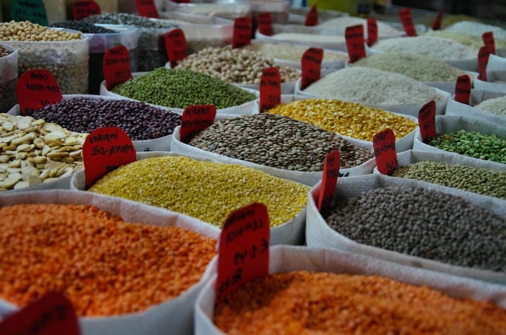 Bags of vibrant grains and spices on display in a bustling market setting.